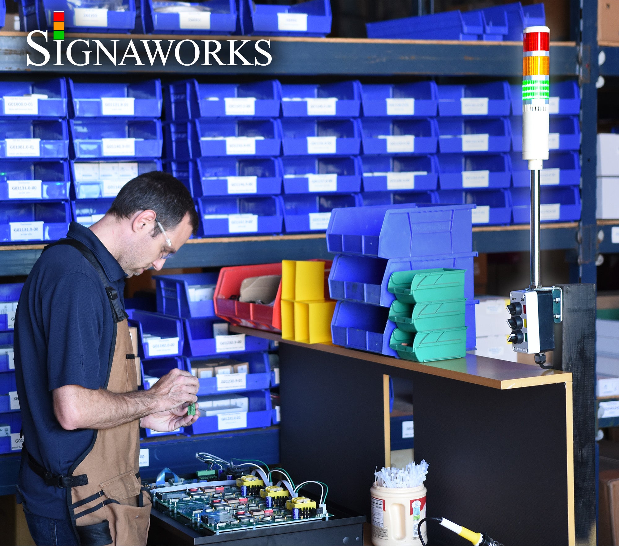 Man manufacturing electronics near a featuring a Red, Amber and Green industrial signal light.