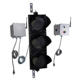 Angled perspective of a wireless traffic light system with LED lights off and accompanying control box transmitter with mirrored pilot light and 3-position switch ton a white background.