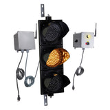 Angled perspective of a wireless traffic light system with amber LED light on and accompanying control box transmitter with mirrored pilot light and 3-position switch ton a white background.