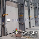 A loading dock with oversized closed garage doors and yellow industrial swing arm dock lights mounting between garage door entrances.