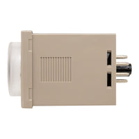 Tan timer with clear dial on left and metal pins on right.