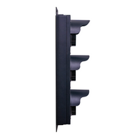 Side profile of a black triple-lens traffic light on a white background.